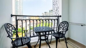En balkon med gelænder, to stole og et lille bord.