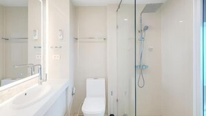 Et moderne badeværelse med en hvid vask, toilet og brusekabine med glasvægge.