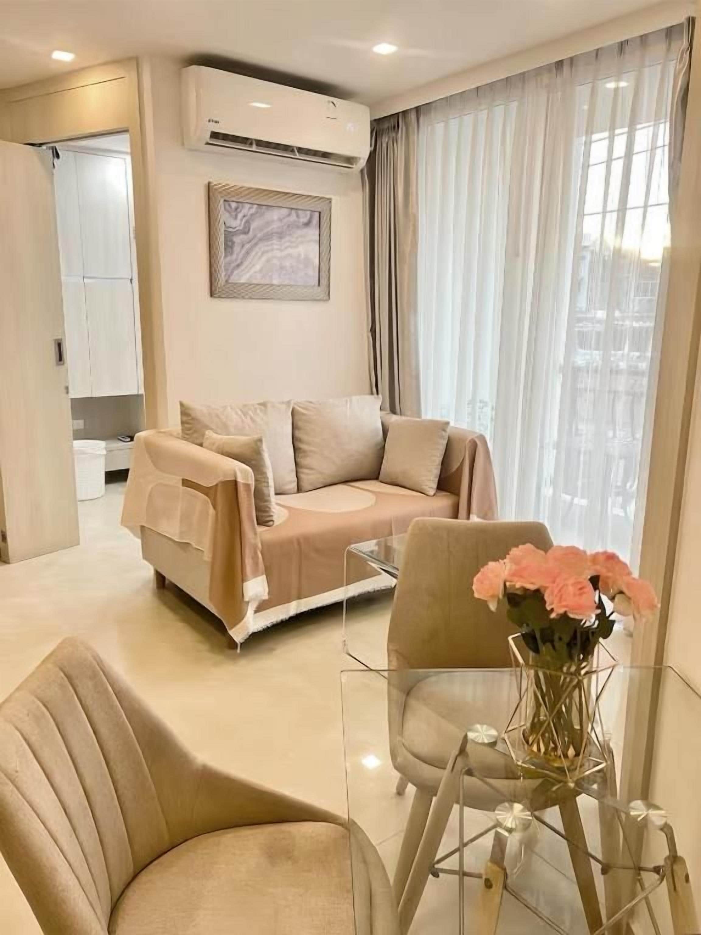 A modern living room with a sofa, a glass coffee table, and a vase of flowers.