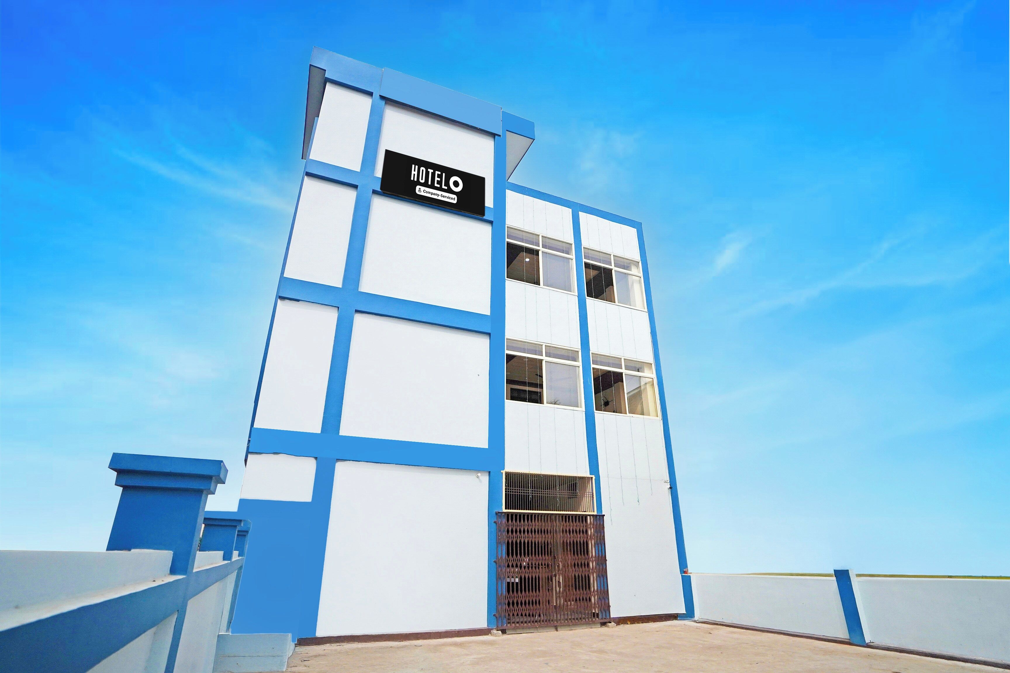 A modern hotel building with a sign reading 'HOTEL' and a company-serviced logo.