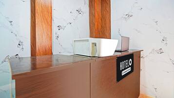 A reception desk with a marble wall background, a wooden panel, and a sign indicating 'HOTEL & Company Serviced'.