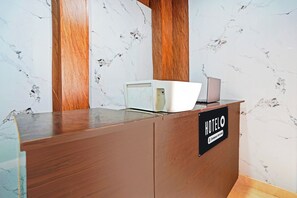 Un mostrador de recepción con un fondo de pared de mármol, un panel de madera y un letrero que indica 'HOTEL & Company Serviced'.