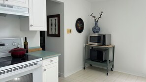 A kitchen with a stove, microwave, and a small refrigerator on a cart. - Bright & Cozy - The White Rock Gateway (Surrey)