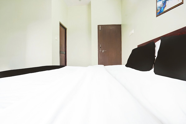 Una habitación de hotel con una cama, una puerta y una obra de arte colgada en la pared.