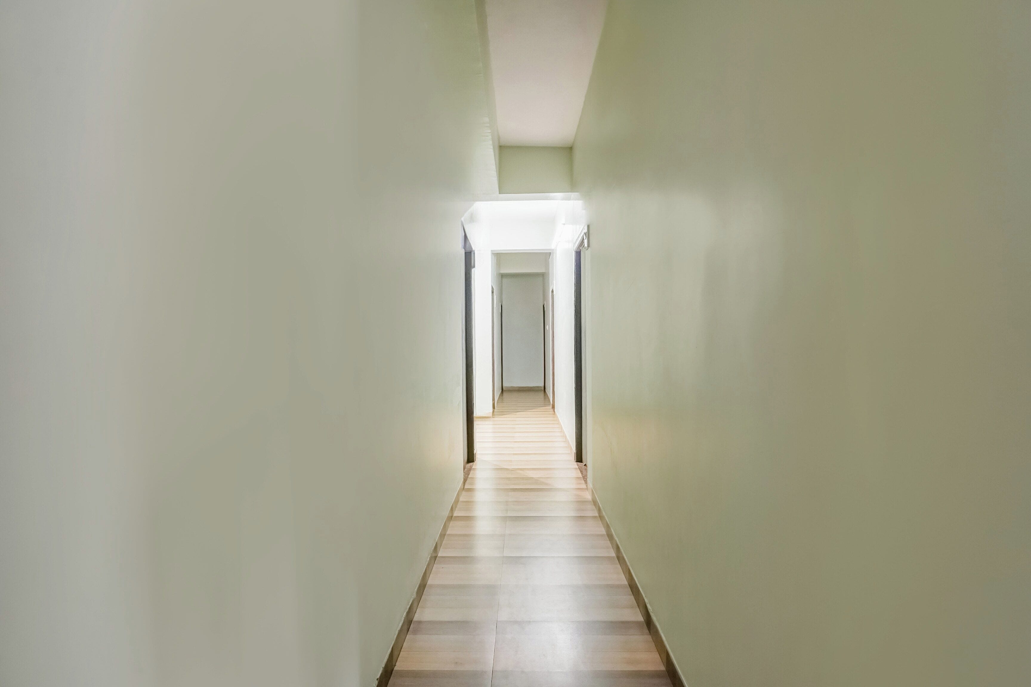 A narrow hallway with a light source at the end, leading to a door.