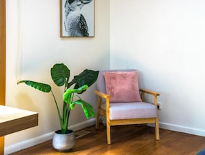 A room with a wooden chair, a potted plant, and a wall-mounted picture. - Camellia Cottage (Olinda)