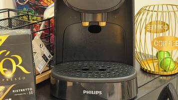 Eine Kaffeemaschine mit Firmenlogo, einer Tassehalterung und einer Kaffeeverpackung auf einer Arbeitsfläche.