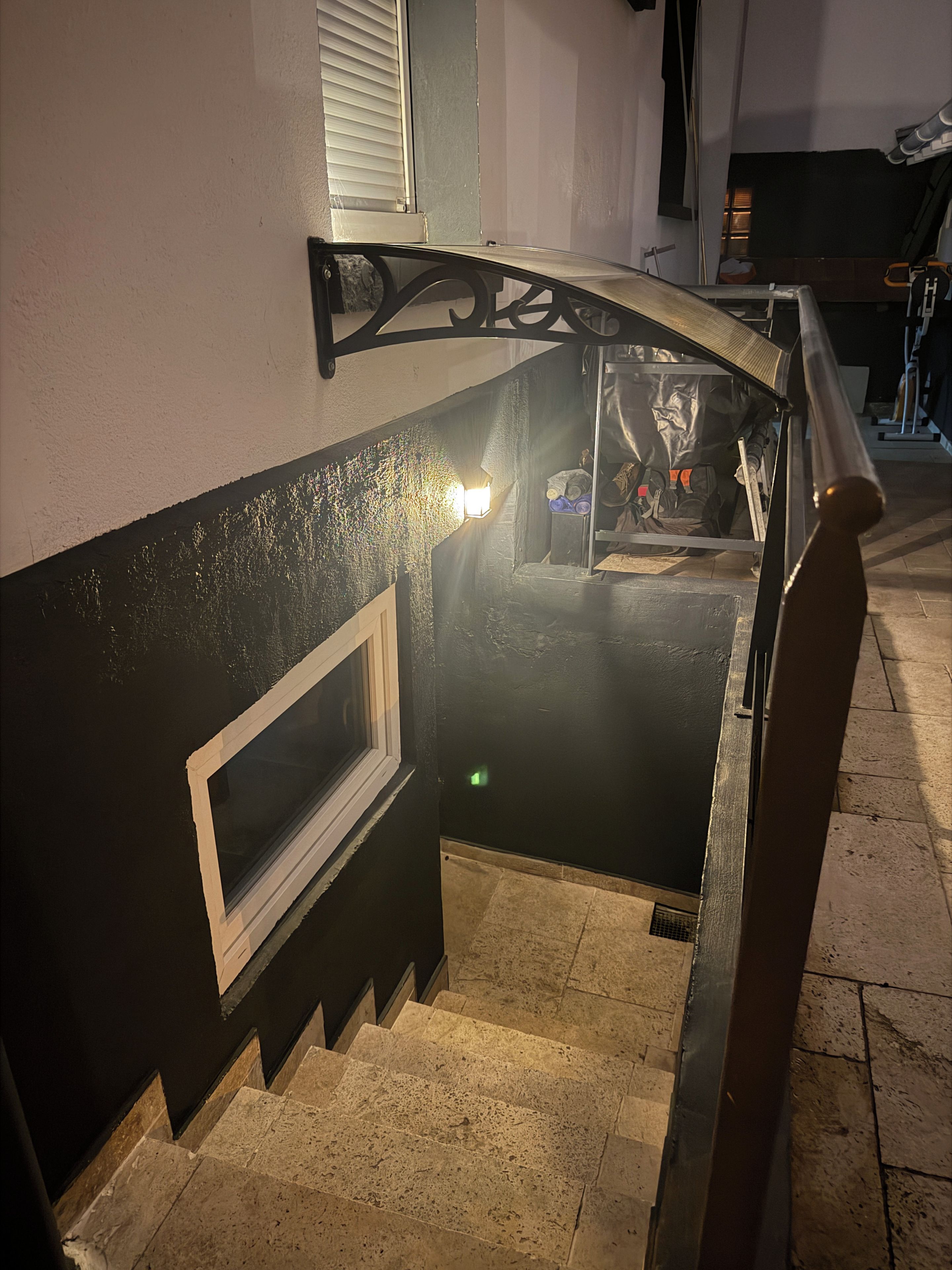 A staircase with a handrail, a window, and a wall-mounted light fixture.