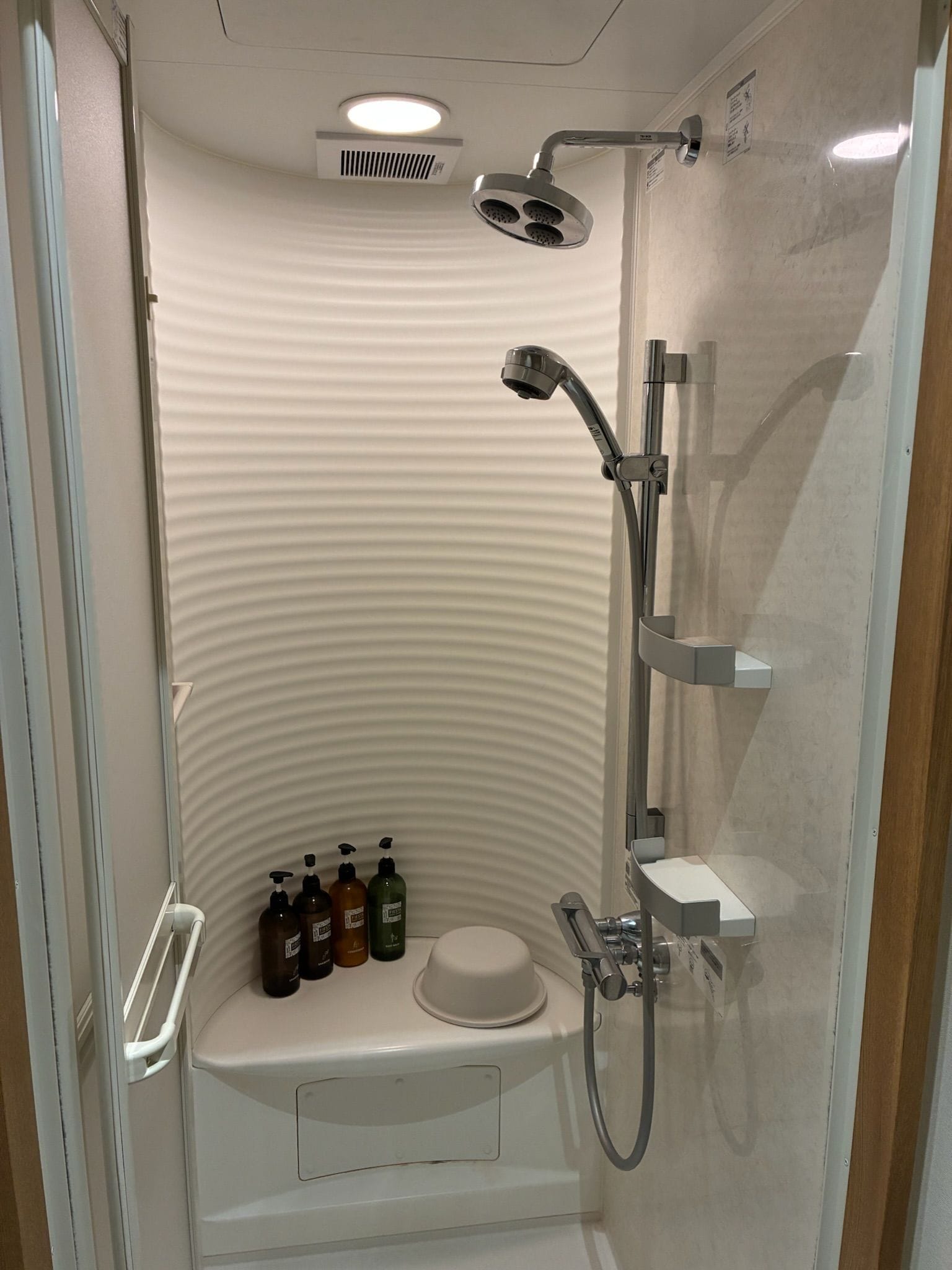 Un box de ducha moderno con cabezal de ducha de mano, grifo empotrado en la pared y asiento integrado.