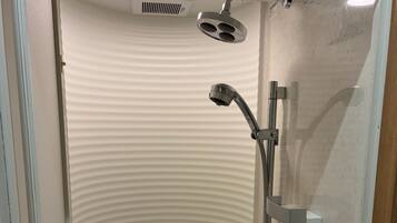 Un box de ducha moderno con cabezal de ducha de mano, grifo empotrado en la pared y asiento integrado.