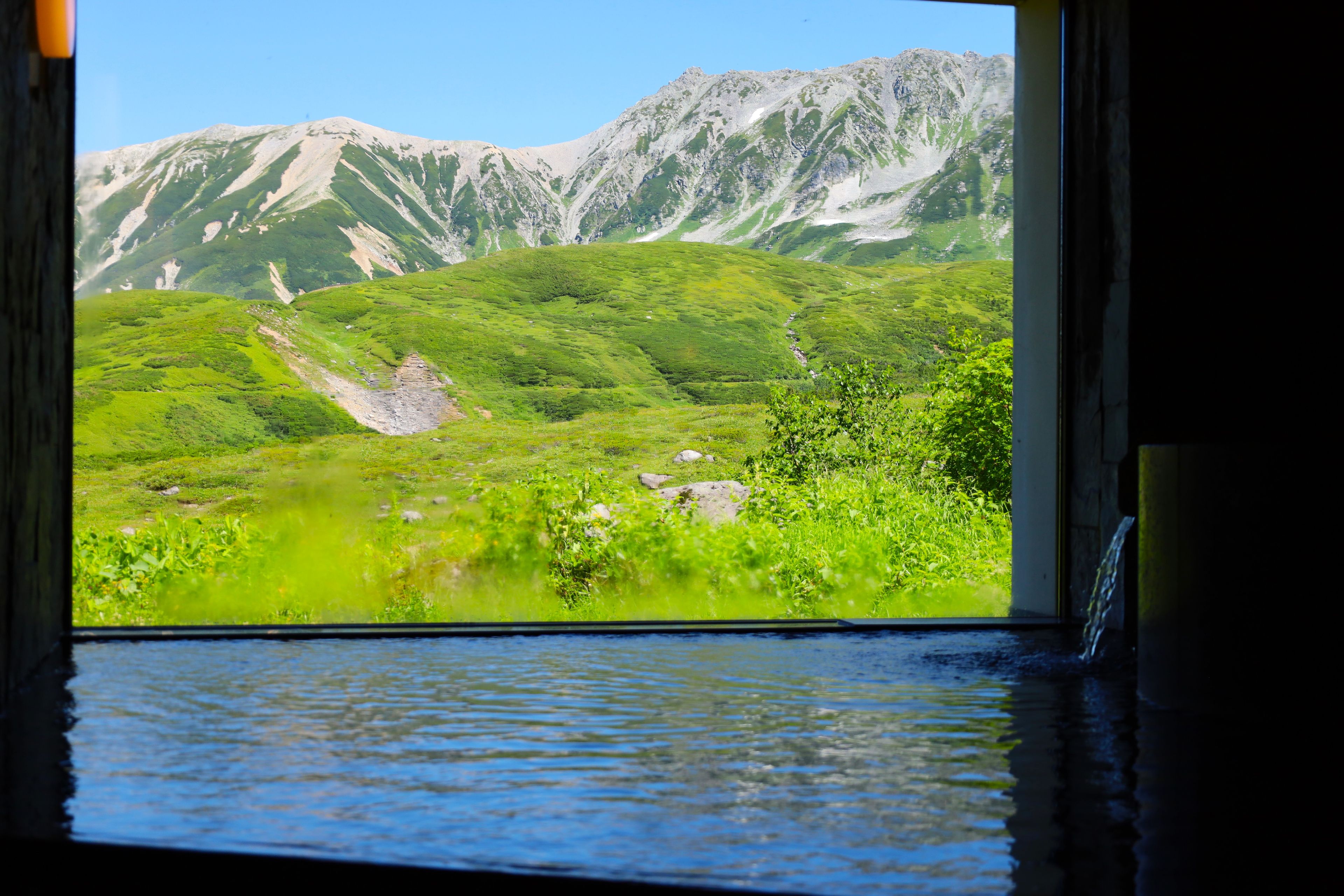 Vista desde una ventana a un paisaje montañoso con cielo despejado.