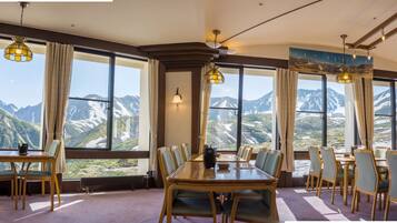 Un comedor con vistas a la montaña, ventanas amplias y mobiliario de madera.