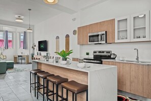 A modern kitchen with a central island, bar stools, a microwave, and a stove. - Grand Galleria — Old San Juan Private Patio (San Juan)