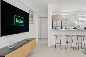 A modern kitchen with a built-in refrigerator, a sink, and a bar area with stools. - Private Patio 2BR Near Ocean Park Beach (San Juan)