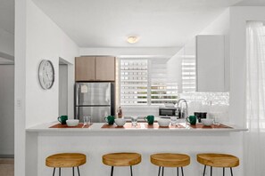 A modern kitchen with a central island, stainless steel appliances, and bar stools. - Private Patio 2BR Near Ocean Park Beach (San Juan)