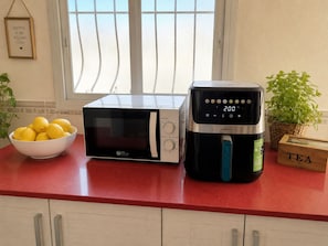 A kitchen counter with a microwave, an air fryer, and a bowl of lemons.