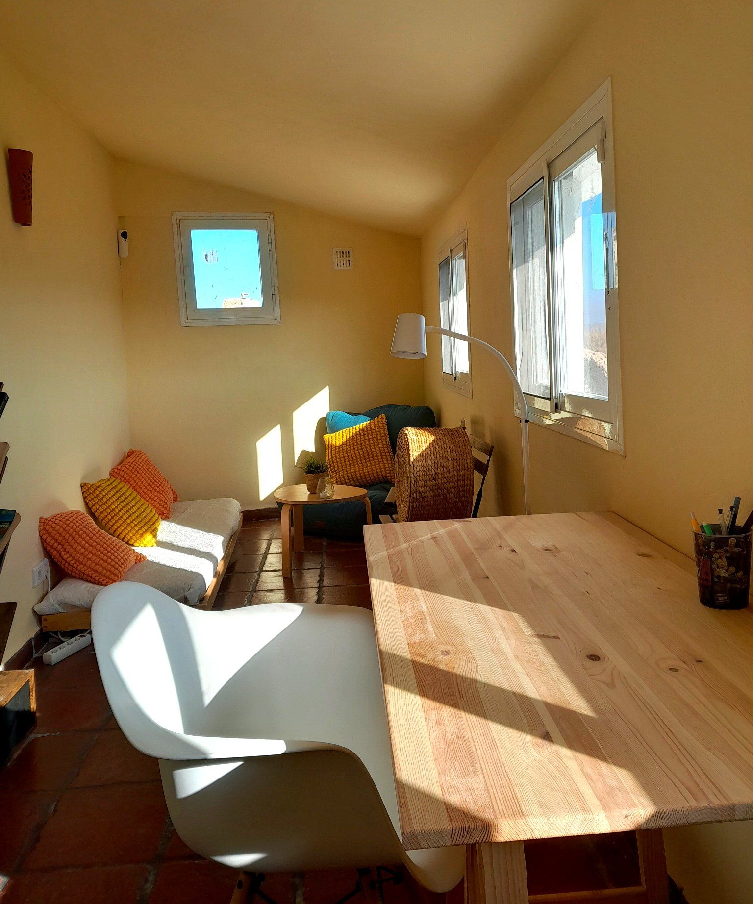 Een kamer met een houten tafel, een bank en een raam met jaloezieën.
