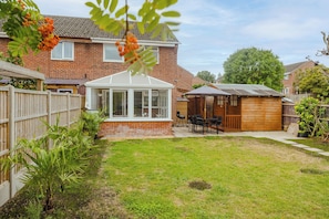 A residential property with a brick house, a conservatory, a wooden shed, and a well-maintained lawn. - Tor View-Stunning Home near Glastonbury (Street)