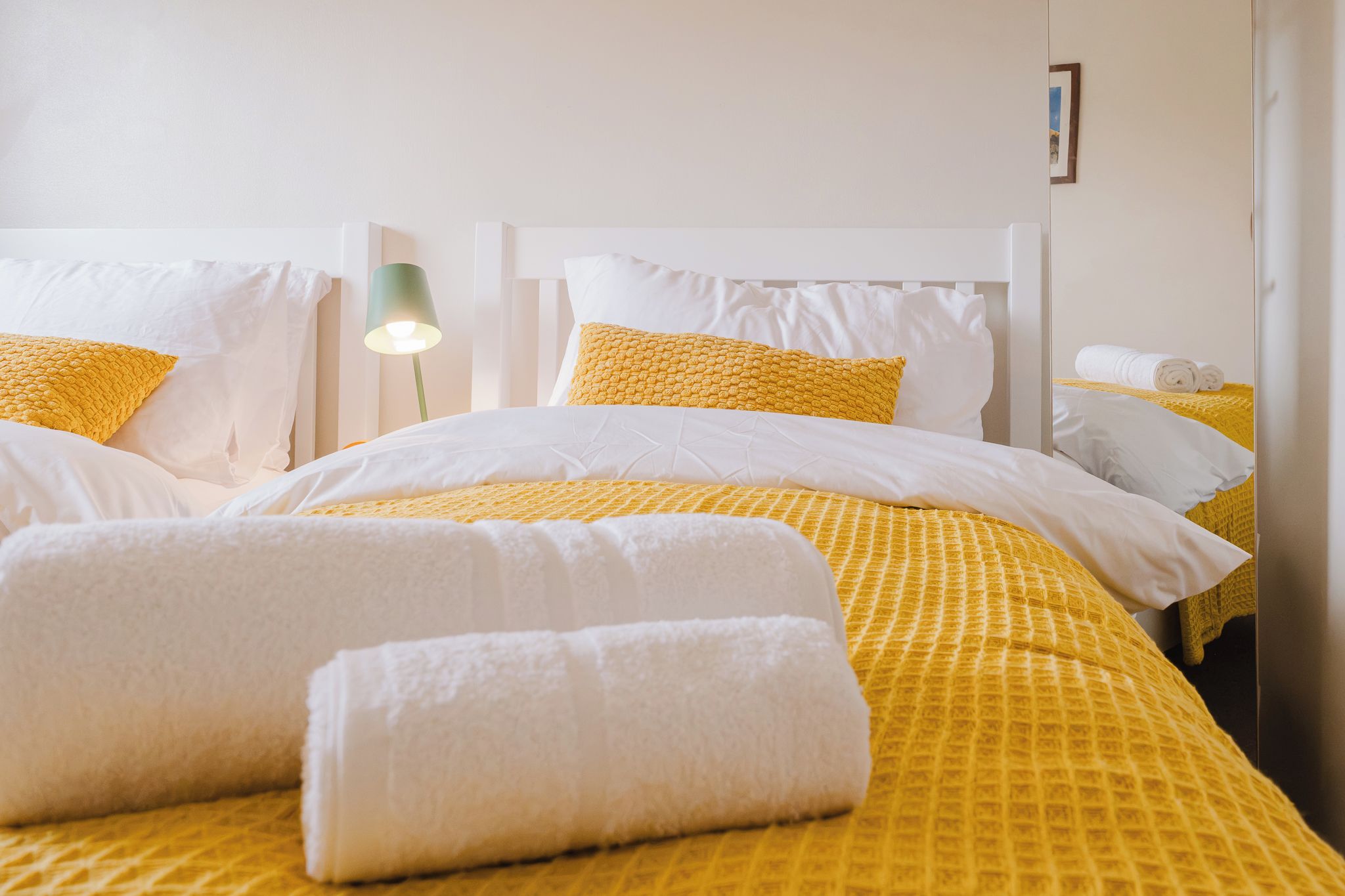 A hotel room with a bed, pillows, and a lamp.