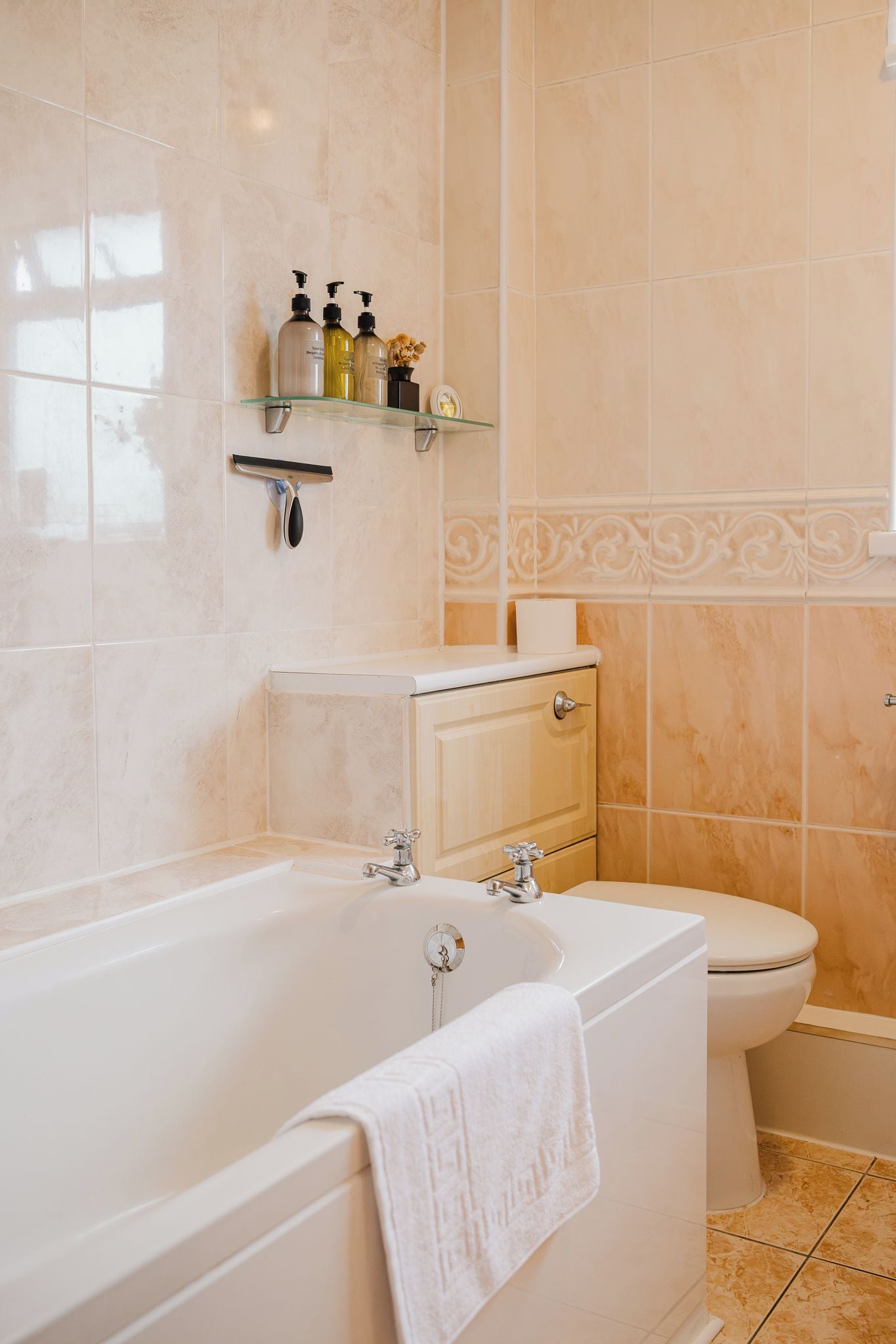 Un baño con bañera, inodoro y un estante con artículos de aseo.