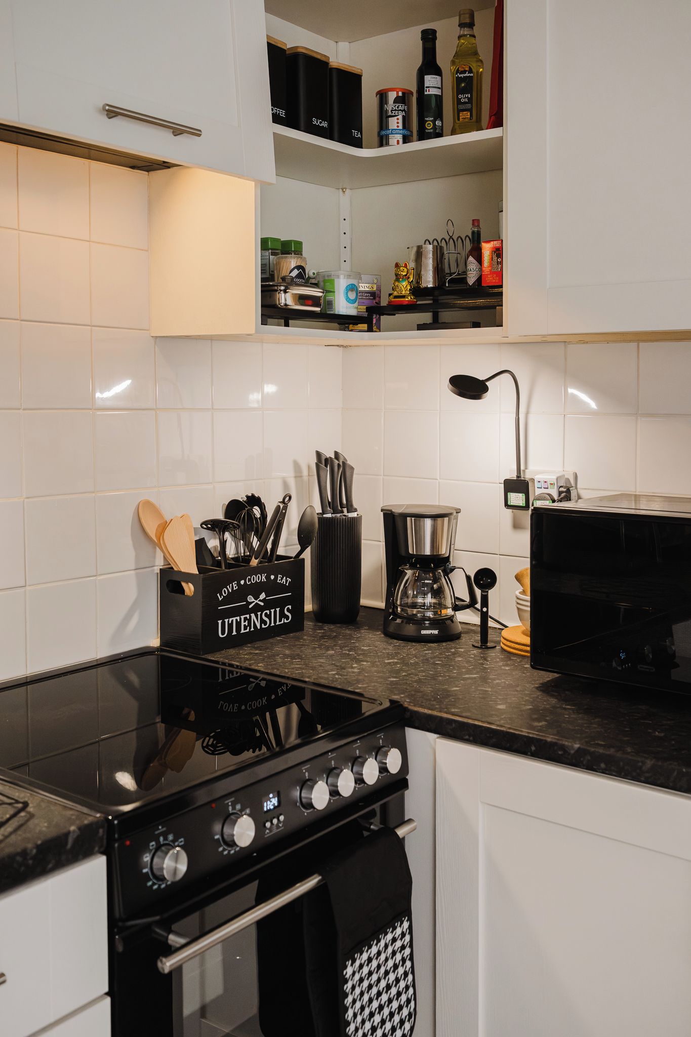 A modern kitchen with a gas stove, coffee maker, and various kitchen utensils.