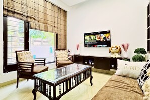 A living room with a sofa, chairs, a coffee table, a TV, and decorative items. - Nivera Stays 4BHK Ground Floor Home near Fortis, IGI Airport, South Delhi (New Delhi)