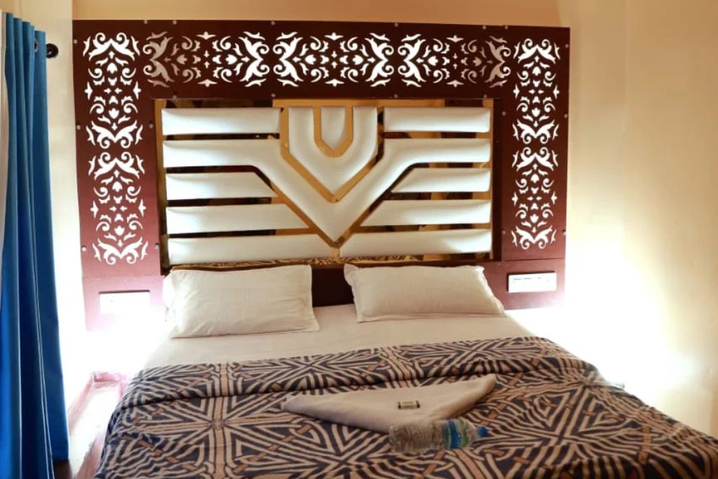 Une chambre d’hôtel avec une tête de lit décorative, une couvre-lit à motifs et un lit parfaitement fait.
