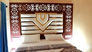 Une chambre d’hôtel avec une tête de lit décorative, une couvre-lit à motifs et un lit parfaitement fait.
