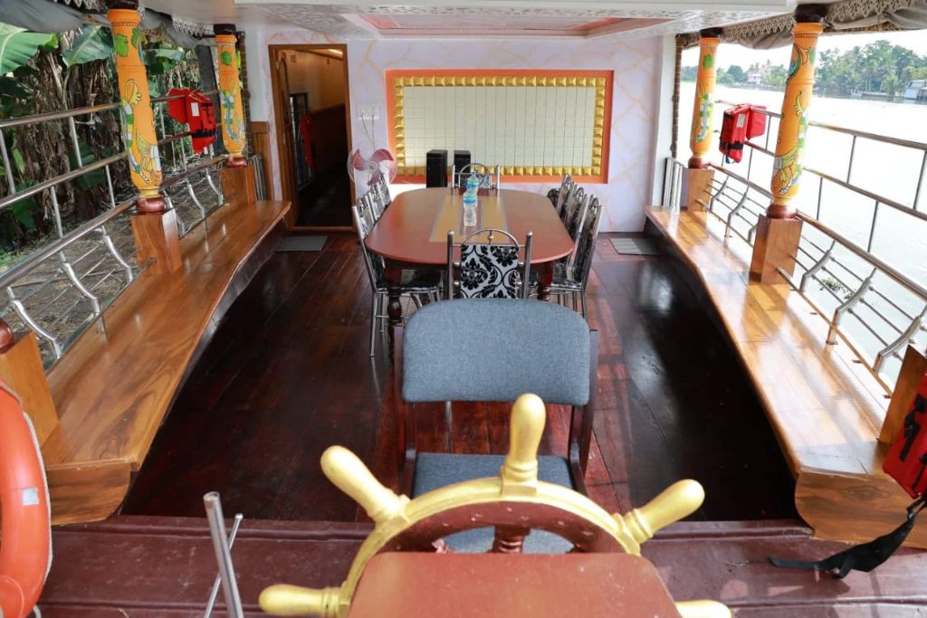 Un espace repas avec une longue table, des chaises et un gouvernail de bateau.