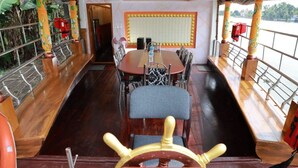 Un espace repas avec une longue table, des chaises et un gouvernail de bateau.