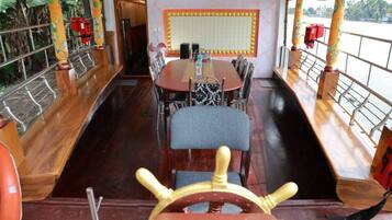 Un espace repas avec une longue table, des chaises et un gouvernail de bateau.