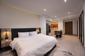 A modern hotel room with a large bed, a desk, and a kitchenette. - Amazing Deal at Elevens by Spacey #4 (cairo)