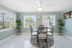 A dining area with a round table, chairs, a ceiling fan, and potted plants. - Adorable and Spacious Pool Home with a Private Fenced Yard in Lake Worth (Lake Worth Beach)