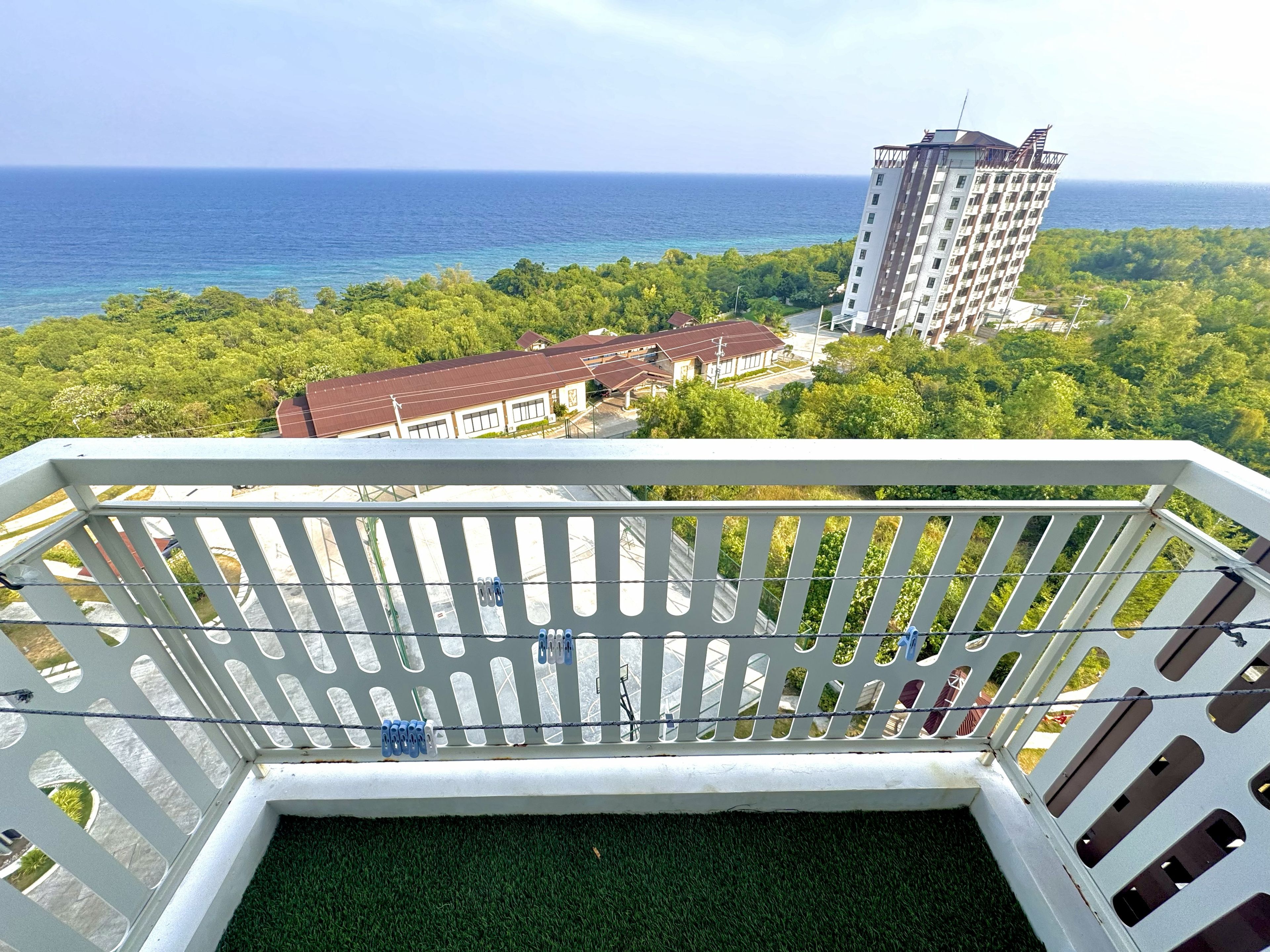 A balcony with a view of the ocean and a tall building in the distance.