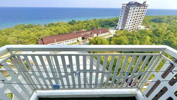 A balcony with a view of the ocean and a tall building in the distance.
