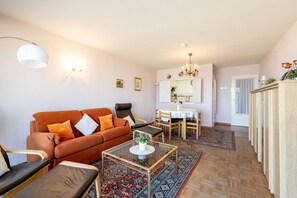 Uma sala de estar com sofá, mesa de centro e área de jantar com mesa e cadeiras.