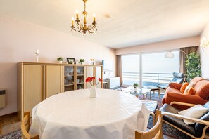 A hotel room with a round dining table, a sofa, a cabinet, and a large window with a view. - Apartment in Blankenberge by the Beach (Blankenberge)