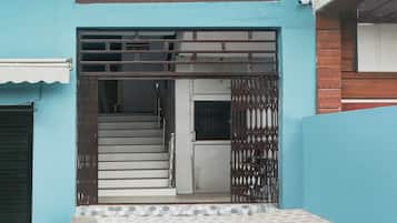 A residential entrance with a metal gate, a staircase leading to a door, and a tiled floor.