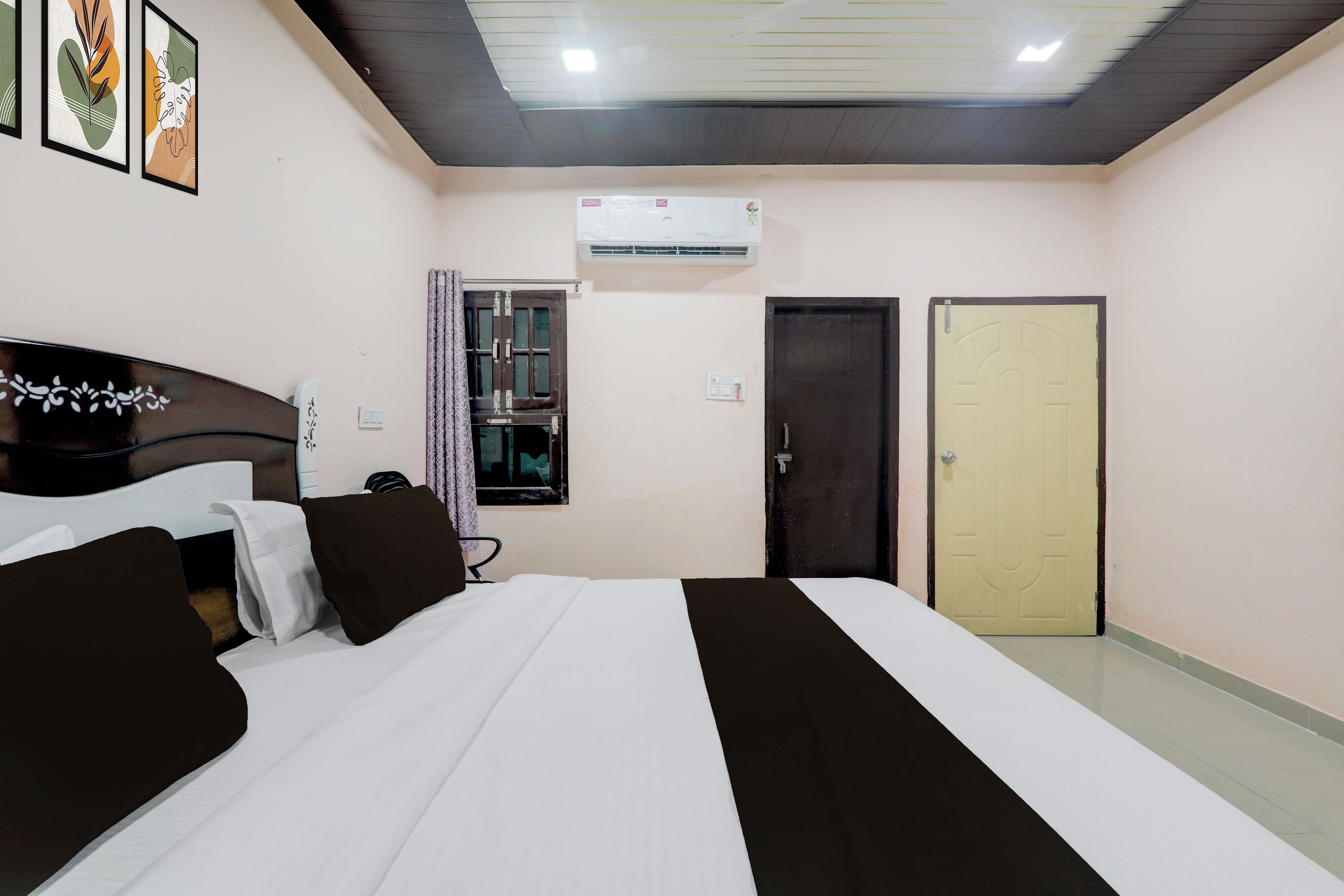 Een hotelkamer met een bed, een kledingkast, een raam met gordijnen, een airconditioning en een deur.
