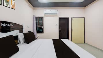 Een hotelkamer met een bed, een kledingkast, een raam met gordijnen, een airconditioning en een deur.