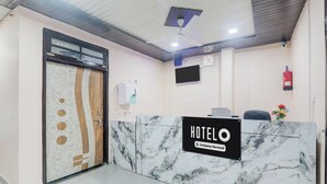 A hotel reception area with a marble counter, a reception desk, a mounted television, and a fire extinguisher on the wall. - Hotel O Shri Buddheshwar Temple Lucknow (Lucknow)