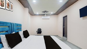 A hotel room with a bed, a chair, a ceiling fan, and a door. - Hotel O Shri Buddheshwar Temple Lucknow (Lucknow)