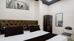 A hotel room with a large bed, a wardrobe, a chair, and three wall-mounted paintings. - Hotel O Shri Buddheshwar Temple Lucknow (Lucknow)