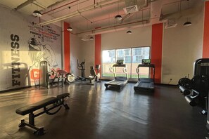 Ein Fitnessraum mit Trainingsgeräten, einer Sitzbank, Laufbändern und motivierenden Wandbildern.