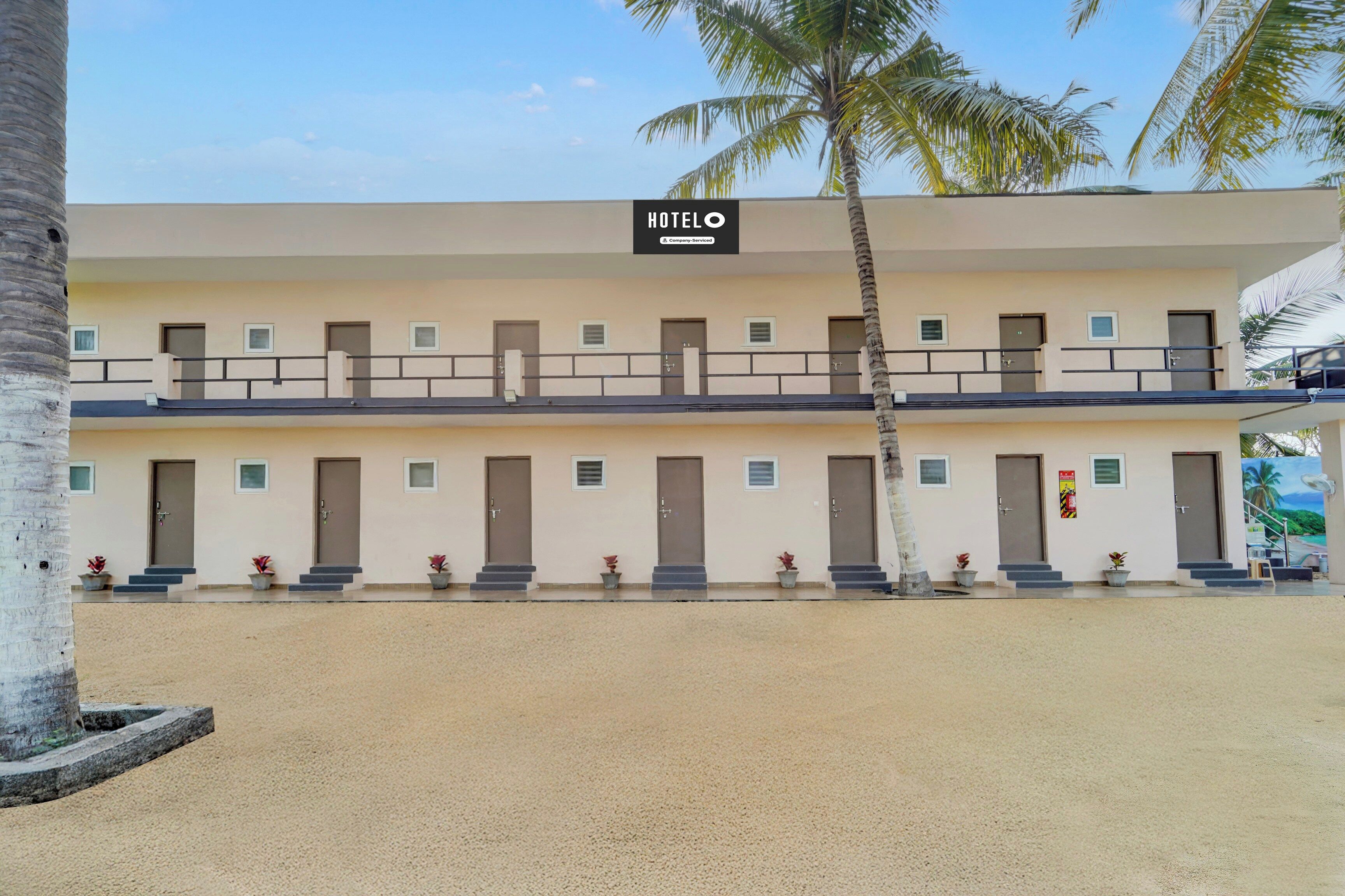 Un hotel con cartel, varias puertas y un balcón con barandillas.