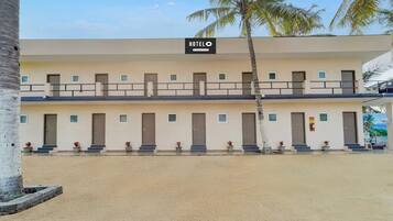 Un hotel con cartel, varias puertas y un balcón con barandillas.