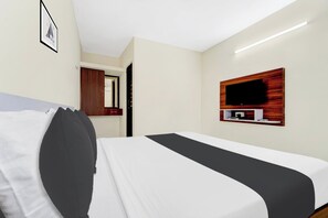 A hotel room with a bed, a television mounted on the wall, and a door leading to another room. - Super Hotel O Avinashi Road Coimbatore (Coimbatore)