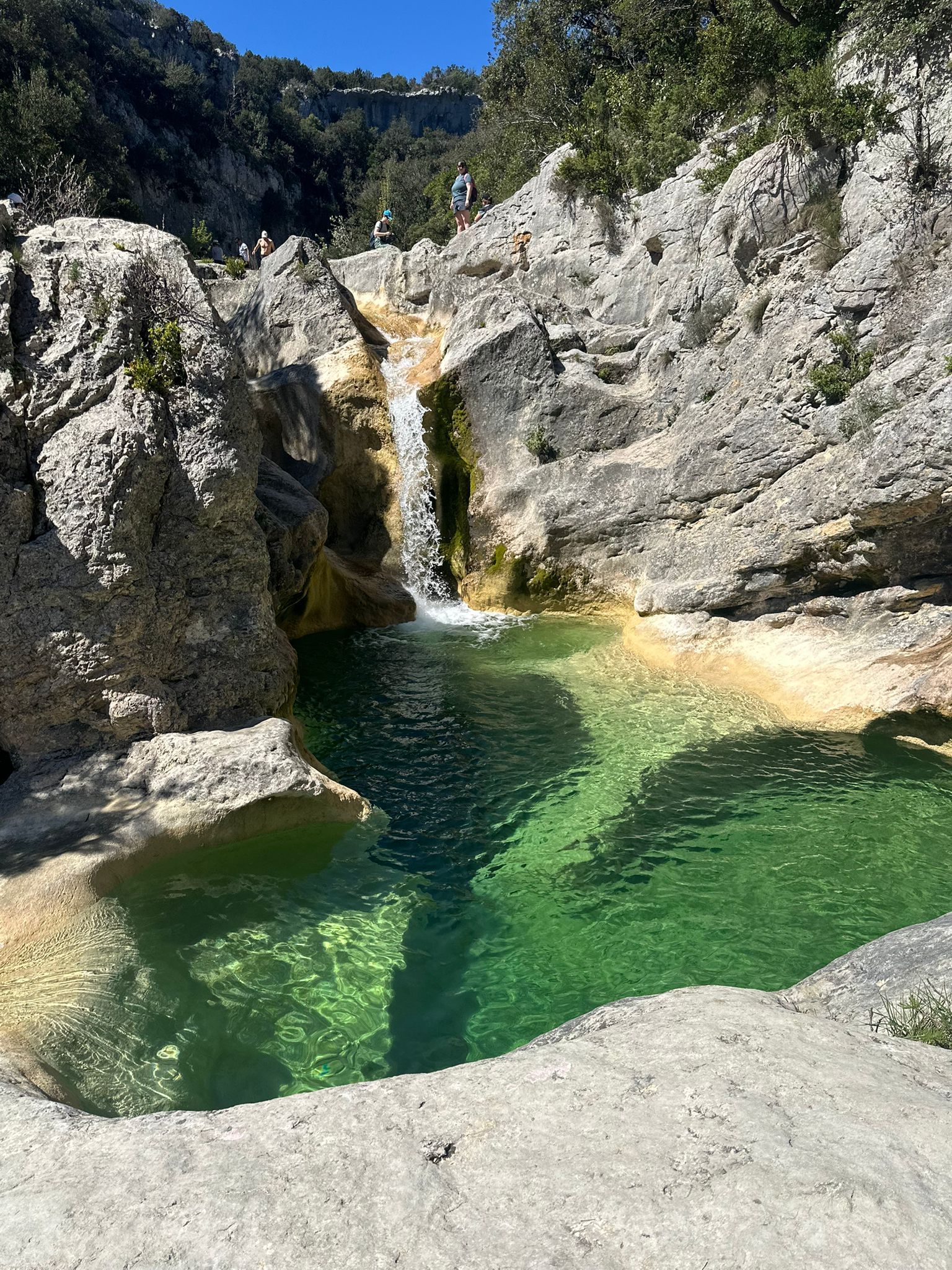 Une piscine naturelle entourée d’un paysage rocheux, avec une cascade.