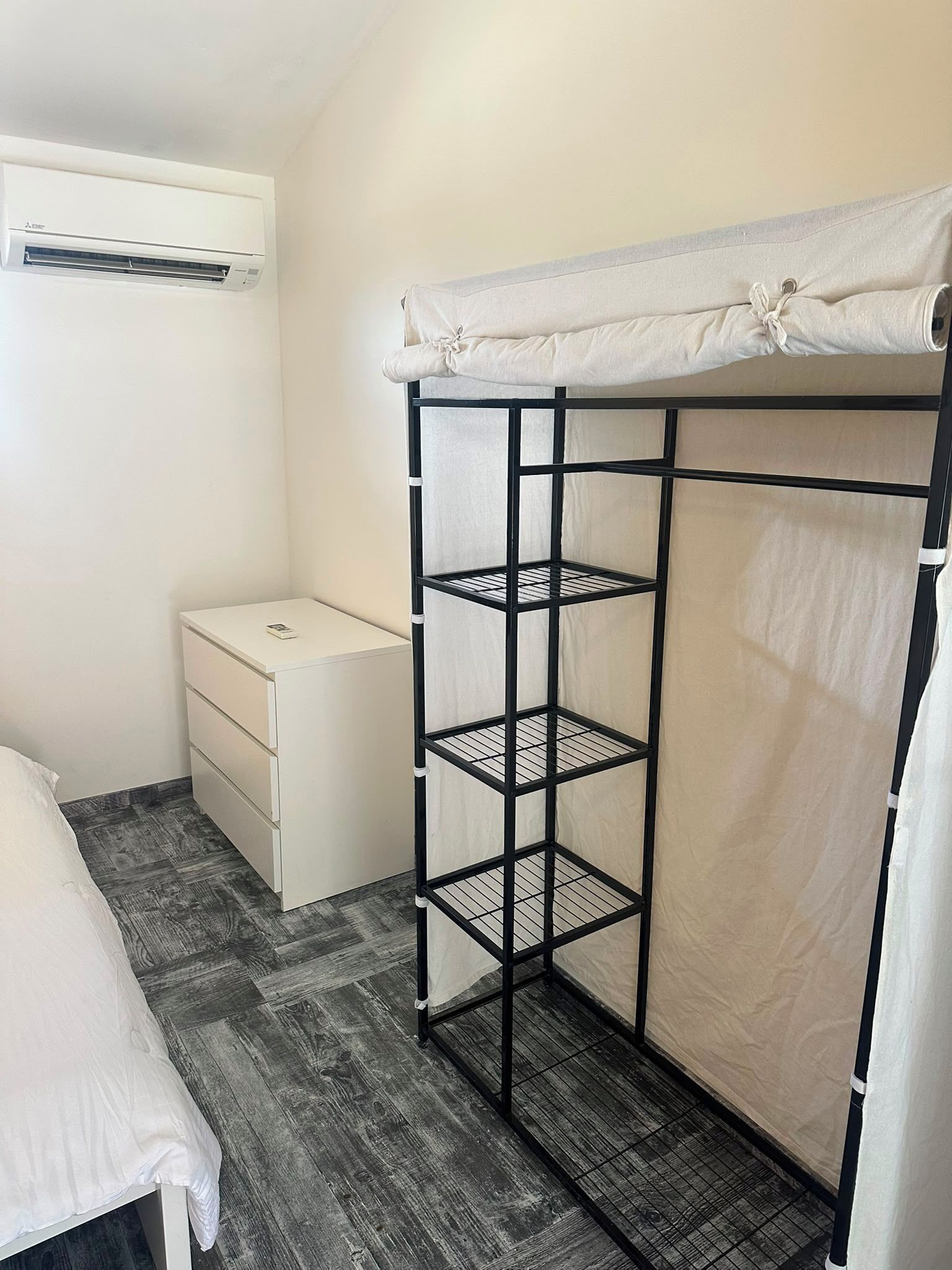 Ein Schlafzimmer mit Etagenbett, Nachttisch, Kommode und Klimaanlage.