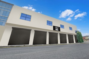 A building with a sign reading 'Collection & Company Serviced' and multiple garage doors. - OYO Collection O Ratan Lal Nagar (Kanpur)